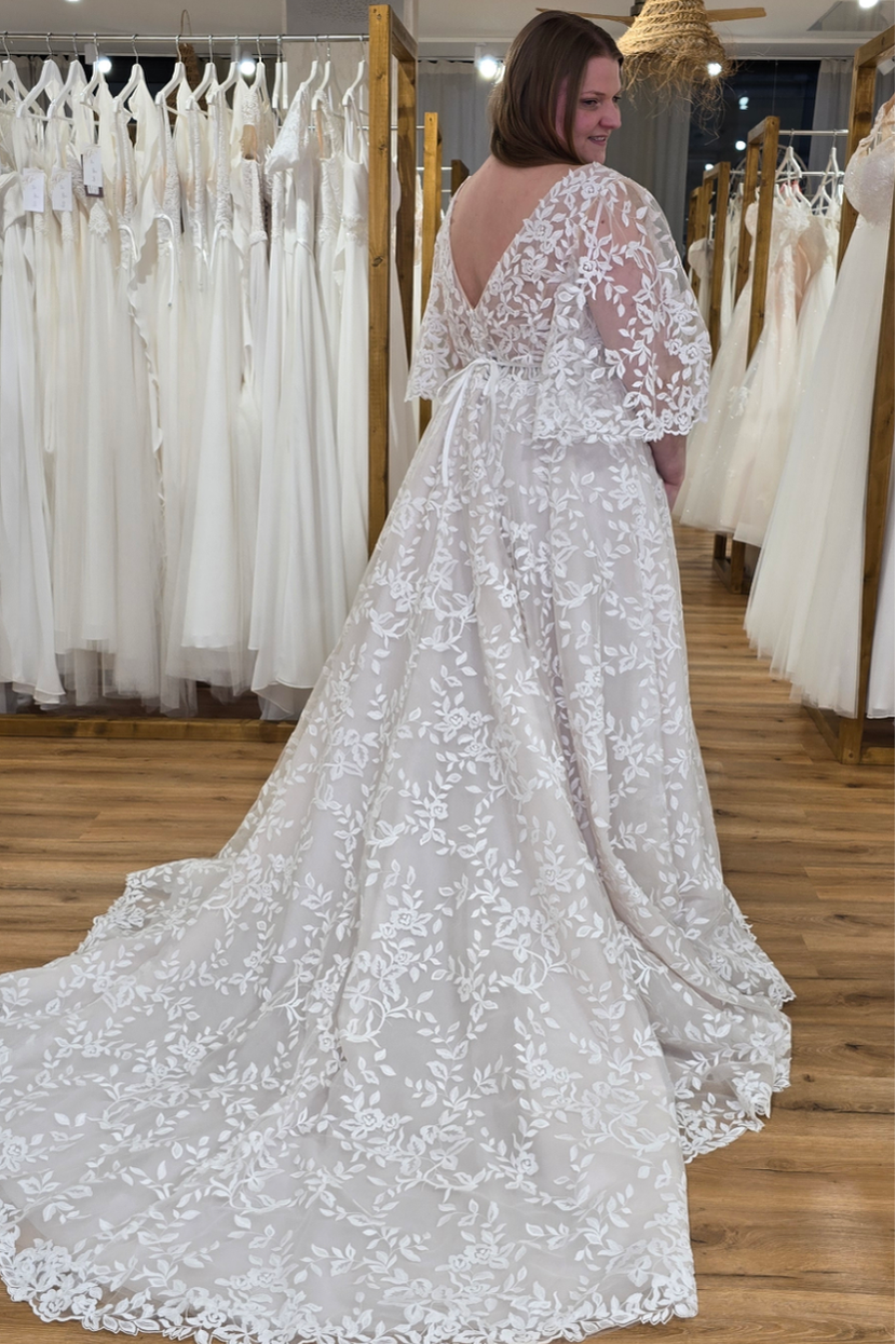 Glückliche Braut in Brautkleid AJA-NA mit langer Schleppe mit floralem Muster große Größen