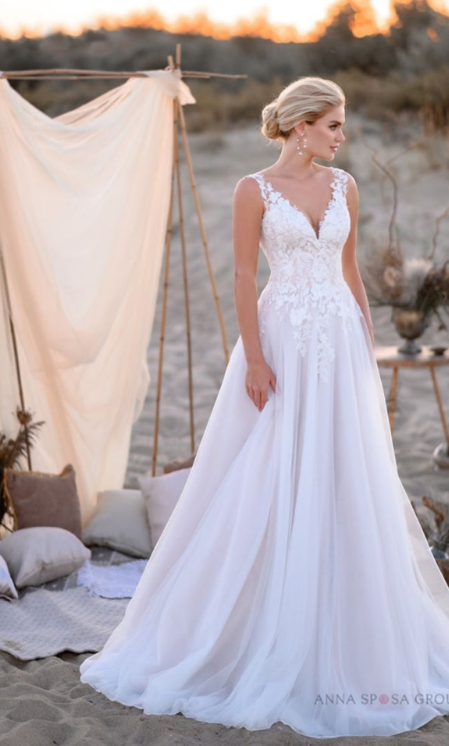 Eine Braut in "Susannas Brautmode" trägt das "Elena" A-Linien-Brautkleid mit V-Ausschnitt und Spitzenapplikationen, eine romantische Wahl für eine Hochzeit in Leverkusen oder dem Rheinland.