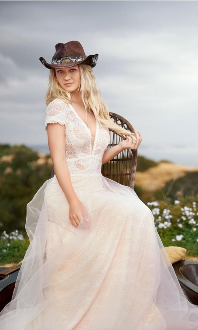 Braut in Boho-Spitzenkleid, vervollständigt mit einem Cowboyhut, verleiht der traditionellen Hochzeitsmode einen Hauch von Wildwest-Romantik